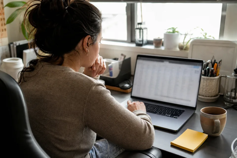 Sales rep at a home office desk working through a contact spreadsheet on a laptop